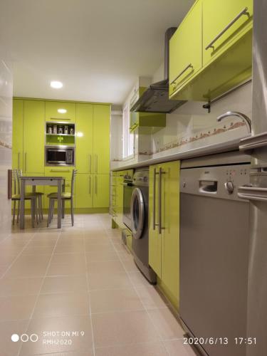 uma cozinha com armários verde lima e uma mesa em Habitación individual con baño privado en casa particular em Madri