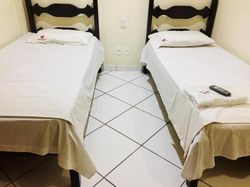 two beds sitting next to each other in a room at Hotel Oliveira - By UP Hotel in Ipatinga