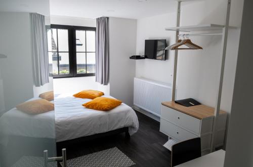 a bedroom with a bed with orange pillows on it at PANACHE - BIKE EN SLEEP HOTEL in La-Roche-en-Ardenne