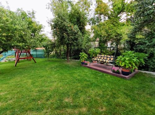 a yard with a bench and trees and a swing at Kishíd Vendégház Pilismarót in Pilismarót
