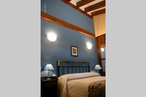 a bedroom with a bed and a blue wall at Casa del Portalón in Ituero y Lama