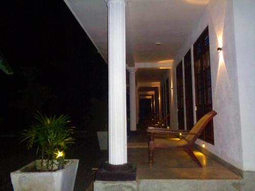 a bench on the porch of a house at night at New Holiday Reach in Unawatuna