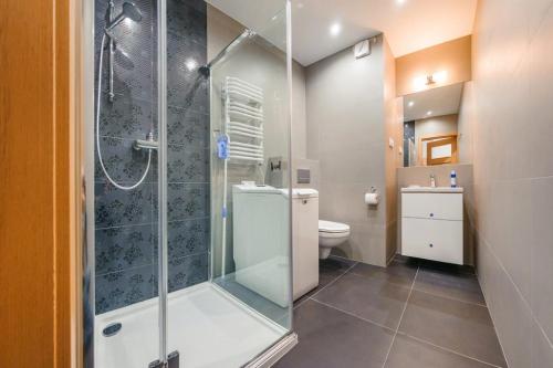 łazienka z przeszklonym prysznicem i toaletą w obiekcie Apartament4siostry65 w mieście Ustronie Morskie