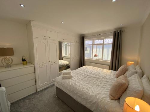 a white bedroom with a bed and a window at COLERIDGE LODGE in Thornton