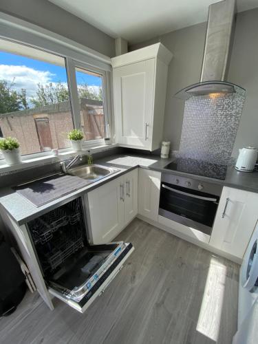 a kitchen with white cabinets and a sink and a stove at COLERIDGE LODGE in Thornton