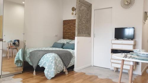 a bedroom with a bed and a tv and a table at Le Paon chaleureux et calme entre Paris et Disneyland in Ozoir-la-Ferrière