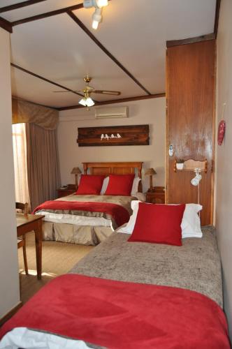 1 dormitorio con 2 camas y almohadas rojas en Marnicus B&B, en Odendaalsrus