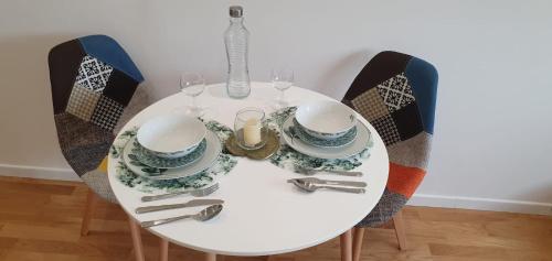 een witte tafel met stoelen en borden en wijnglazen bij Le Paon chaleureux et calme entre Paris et Disneyland in Ozoir-la-Ferrière