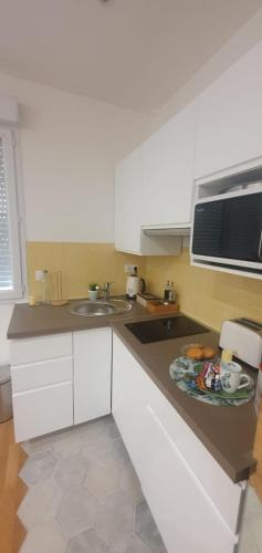 a kitchen with white cabinets and a plate of food on the counter at Le Paon chaleureux et calme entre Paris et Disneyland in Ozoir-la-Ferrière