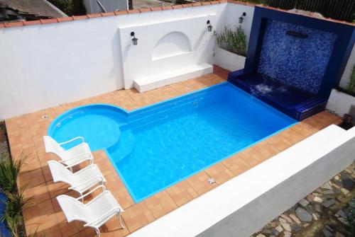 an image of a swimming pool with chairs around it at Pousada Elxadai in Guarapari