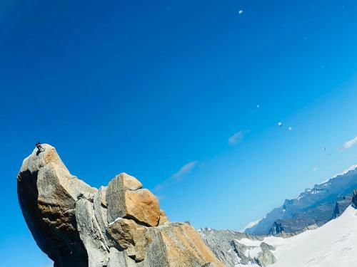 a person sitting on top of a rock on a mountain at Rocky Studio Chamonix Sud in Chamonix-Mont-Blanc