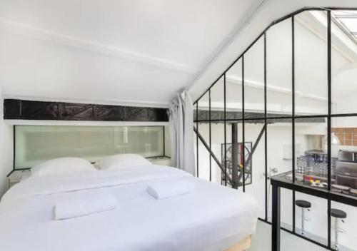a bedroom with a white bed and a balcony at Atelier d Artiste Le Marais Paris - exceptionnel ! in Paris