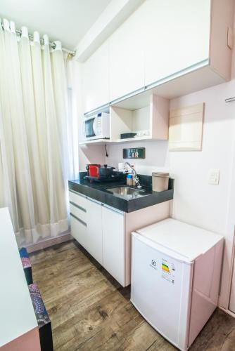 a kitchen with white cabinets and a black counter top at 360 Perdizes in Sao Paulo