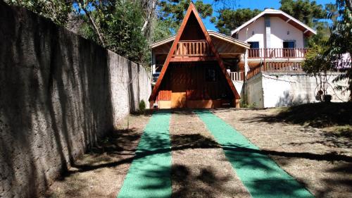 a house with a green pathway in front of a house at Chalé - Sossego 1 in Campos do Jordão