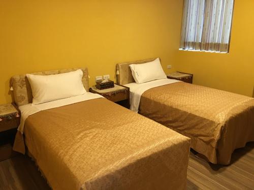 two beds in a room with yellow walls at Sun Moon Lake Tan Hsiang Yu B&B in Yuchi