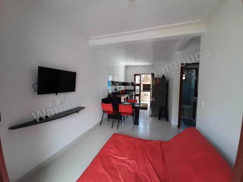 uma sala de estar com um sofá vermelho e uma televisão na parede em Waimea FLATS Itamambuca em Ubatuba