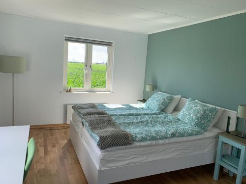 een bed in een witte kamer met een raam bij Field View B&B in Lund