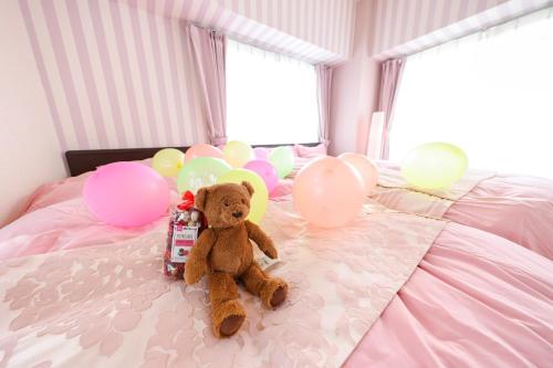 名古屋的住宿－Duetoir 801 / Vacation STAY 7558，一只泰迪熊坐在带气球的床上