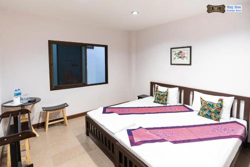 two beds in a room with a table and a window at Ming Shou Boutique House in Phuket Town