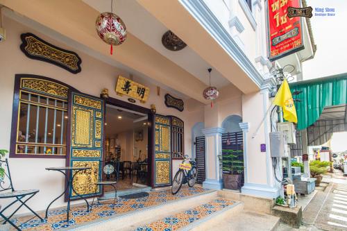ein Gebäude mit einer Tür mit einem Tisch und einem Motorrad, das draußen geparkt ist in der Unterkunft Ming Shou Boutique House in Phuket