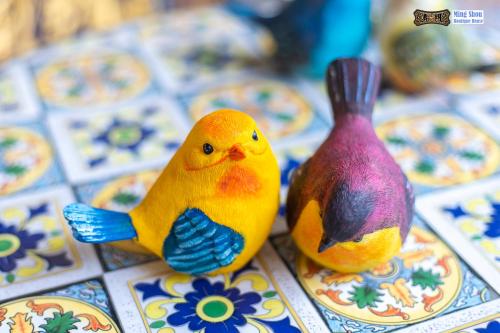 two toy birds sitting next to each other on a table at Ming Shou Boutique House in Phuket Town