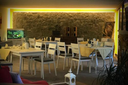 un ristorante con tavoli e sedie bianchi e un muro di pietra di Villa Torre - Atmosfera Romantica a Brenzone sul Garda