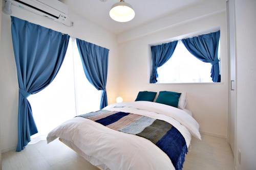 a bedroom with blue drapes and a bed at Vent du Vent401 in Minatogawa