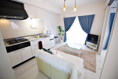 a kitchen with white cabinets and a couch in a room at Vent du Vent401 in Minatogawa