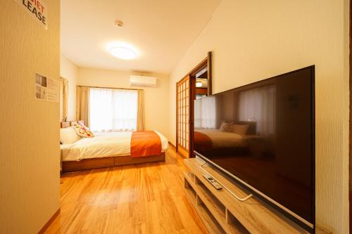 a bedroom with a flat screen tv and a bed at Yufu-no-yu Shiki Iyashi in Yufuin