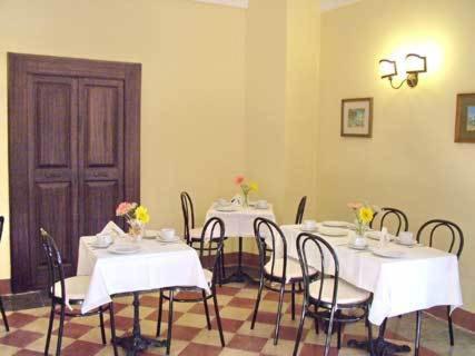 a dining room with white tables and chairs with flowers on them at Palazzo Senape De Pace in Gallipoli