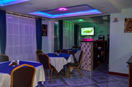 a dining room with tables and chairs and a tv at Kentania Hotel & Spa, Nakuru - Kenya in Nakuru