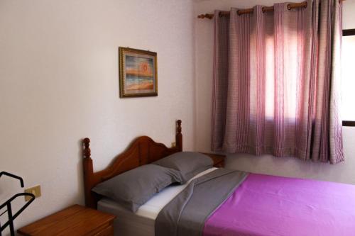 コラレホにあるAppartamento Corralejoのベッドルーム1室(紫のシーツが敷かれたベッド1台、窓付)