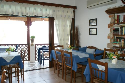 een restaurant met blauwe tafels en stoelen en een balkon bij Pension Akropolis in Kyra Panagia