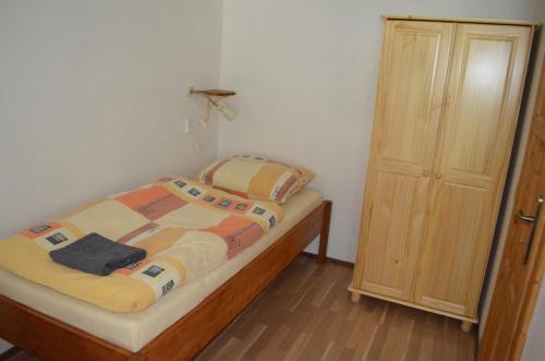 a small bedroom with a bed and a wooden cabinet at Apartmány Kosmonosy, Hradištská 181 in Mladá Boleslav
