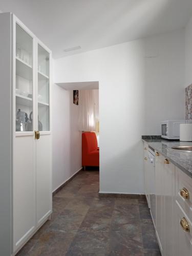 a kitchen with white cabinets and an orange chair at Casa Rural Rectoría de Raspay in Raspay