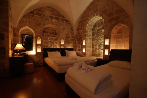 a bedroom with two beds and a stone wall at Zinciriye Hotel in Mardin