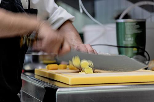 a person cutting up vegetables on a cutting board at Wohlfühlhotel Goiserer Mühle in Bad Goisern