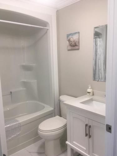 a white bathroom with a toilet and a tub and a sink at Quidi Vidi Retreat 3 in St. John's