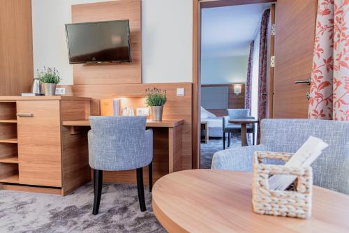 a room with a table and chairs and a tv at Wohlfühlhotel Goiserer Mühle in Bad Goisern