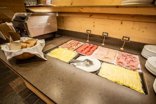 a counter with different types of cheese and bread at Sertorelli Sporthotel in Breuil-Cervinia