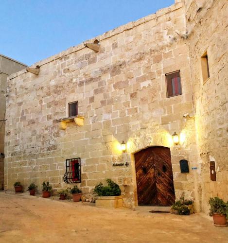 a large brick building with a large wooden door at Molendini in Għarb