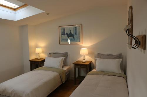 two beds in a room with two lamps at Les Chenevières in Culey
