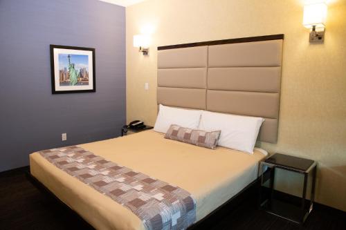 a hotel room with a bed with a large headboard at 7 Days Hotel in Bronx