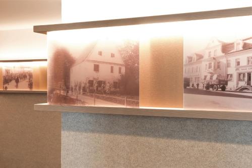 a display of photographs of a building on a wall at Stadthotel Kachelofen in Krumbach