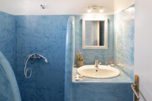 a blue bathroom with a sink and a mirror at Gardenia Hotel in Perissa