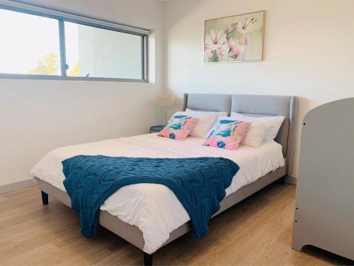 een slaapkamer met een groot bed met roze en blauwe kussens bij Beautiful Home close to Shopping Mall and Train Hornsby in Hornsby