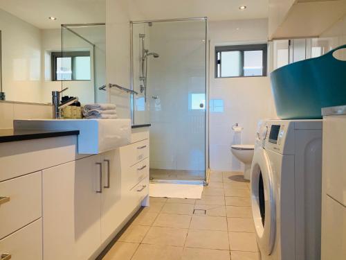 een badkamer met een wasmachine en een douche bij Beautiful Home close to Shopping Mall and Train Hornsby in Hornsby