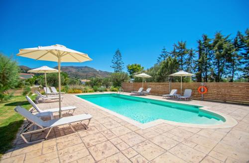 a swimming pool with two chairs and an umbrella at Elegant Villa Zakynthos in Kalamaki