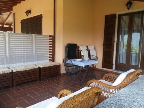 Casa Intignano - Camera con bagno e portico vista lago في تريميزو: فناء مع كراسي الخوص وطاولة على منزل