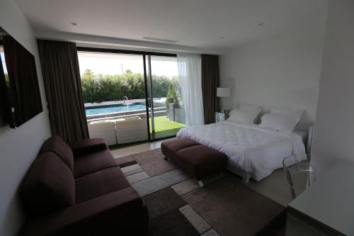 a bedroom with a bed and a couch and a pool at VILLA MIAMI in Les Issambres